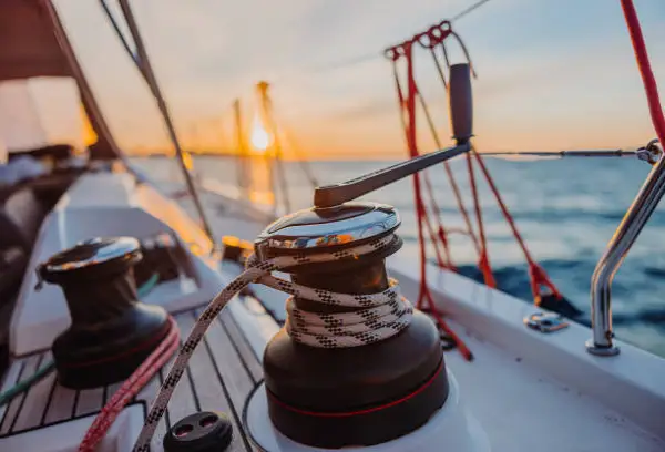 Winch gros plan sur le pont d'un voilier au soleil couchant. Vivre sur un voilier et voyager.